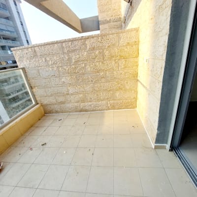 מרפסת עם קיר אבן, מנורה ותקרה חשופה