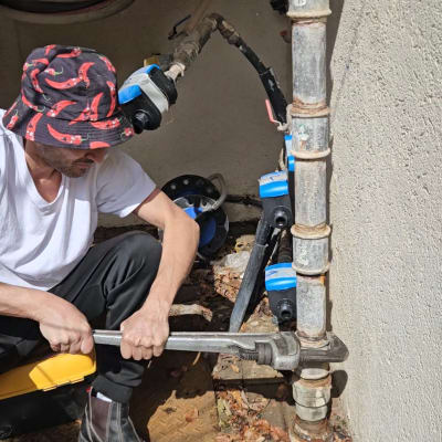 אדם עובד על צינור עם מפתח צינורות