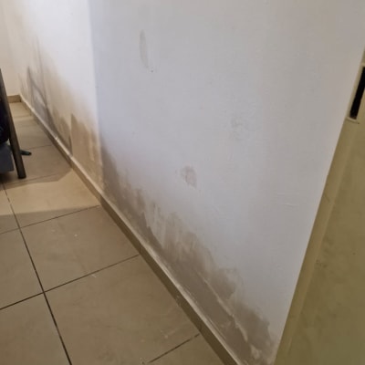 קיר עם סימני רטיבות ותיקונים על הרצפה