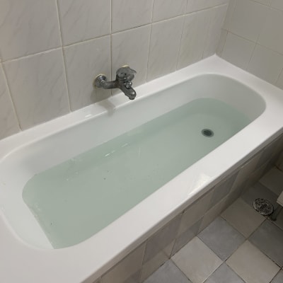 אמבטיה מלאה במים עם ברז קיר קרמי