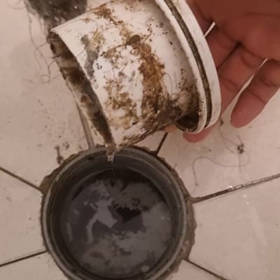 יד מחזיקה מכסה ביוב מלוכלך עם שיער