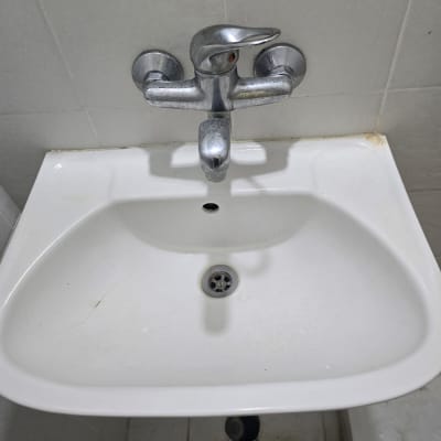 כיור לבן עם ברז מתכת בחדר אמבטיה