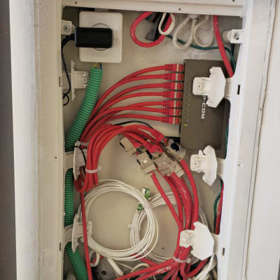 ארון תקשורת עם כבלים אדומים ולבנים מחוברים למתגים