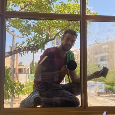 אדם מנקה חלון עם ספוג ומגבת