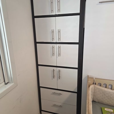 ארון לבן עם ידיות מתכת ליד מיטת תינוק