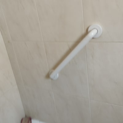 ידית אחיזה לבנה מותקנת על קיר אריחים