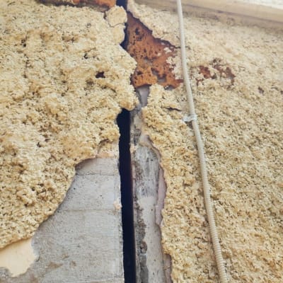 סדק בקיר עם טיח מתקלף וחוט חשמל חשוף