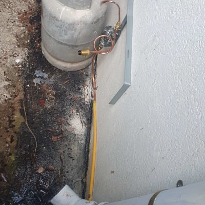 בלון גז מחובר לצינור ליד קיר חיצוני