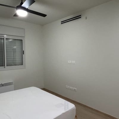 קיר צבוע בלבן בחדר שינה עם חלון