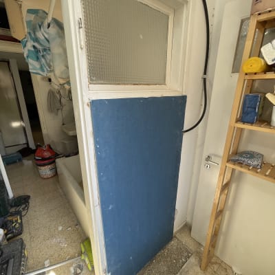 דלת עם לוח עץ כחול, מטאטא וכלי עבודה