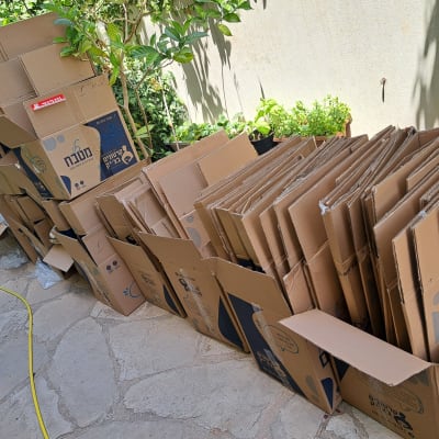 קופסאות קרטון מסודרות בחוץ ליד צמחים ירוקים