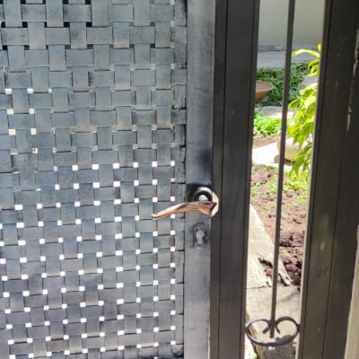 שער מתכת צבוע בצבע שחור עם ידית נחושת