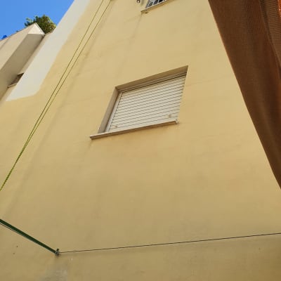 אדם תלוי על חבל צובע קיר חיצוני של בניין