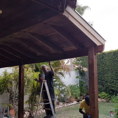 אדם צובע גג עץ בעזרת מברשת וסולם