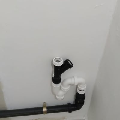 צינור ביוב שחור ולבן מחובר לקיר