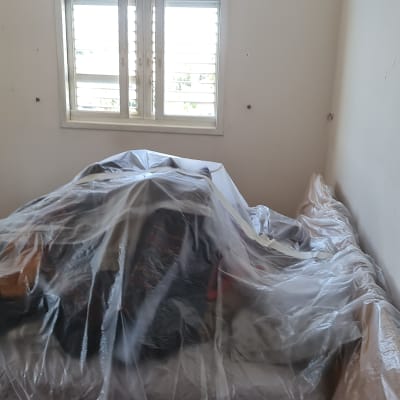 חדר עם רהיטים מכוסים בניילון לקראת צביעה