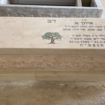 מצבה מאבן עם כיתוב ועץ חרוט במרכז