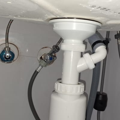 צנרת מתחת לכיור עם חיבורים וצינורות