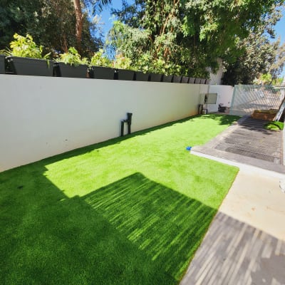 עציצים על קיר, דשא ירוק, עצים ברקע