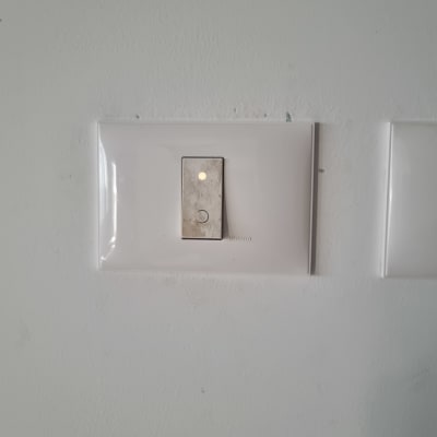 מתג חשמל עם נורית חיווי על קיר לבן