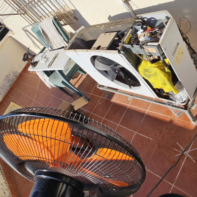 יחידת מזגן מפורקת על מרפסת עם מאוורר וכלים