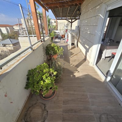 מרפסת עם ריצוף עץ, עציצים ושרפרפים מוערמים