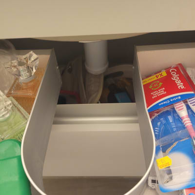 צינור מתחת לכיור עם מוצרי טיפוח