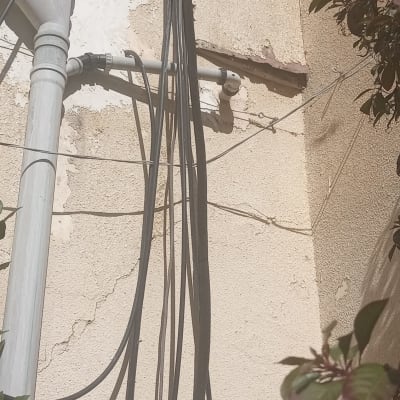 צינורות חיצוניים על קיר בניין עם חוטים חשופים