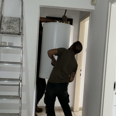 שני אנשים מרימים דוד שמש בחדר צר