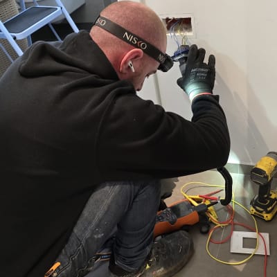 חשמלאי עובד על חיווט בקיר עם כלים חשמליים