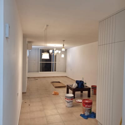 דלי צבע וכלי עבודה בחדר ריק עם קירות צבועים