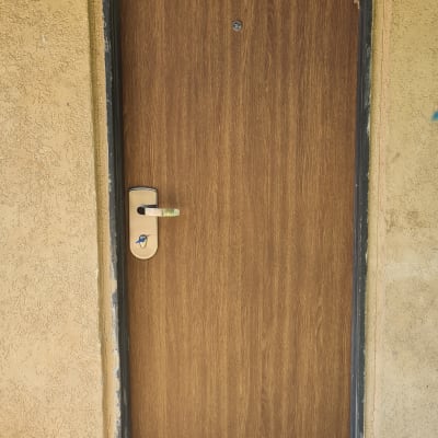 דלת עץ עם ידית מתכת במסגרת קיר טיח