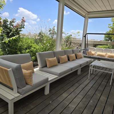 כריות פסים צהובות על ספות אפורות במרפסת