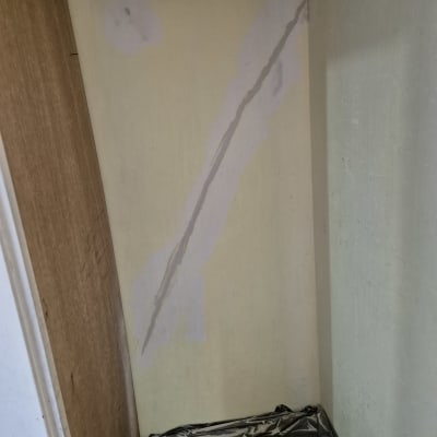 קיר עם תיקוני צבע וטפט פלסטיק על הרצפה