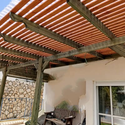 פרגולה מעץ עם קורות עץ אופקיות וגג שקוף