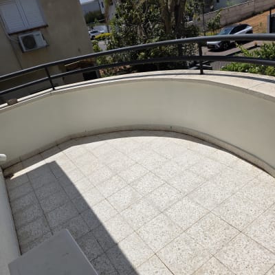 מרפסת עם רצפת אריחים ונוף לעצים ובניינים