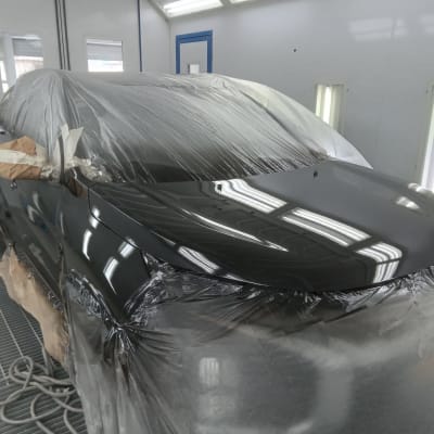 רכב מכוסה בניילון בתהליך צביעה במוסך