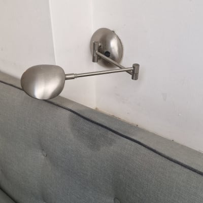 מנורת קיר מותקנת על קיר לבן מעל מיטה