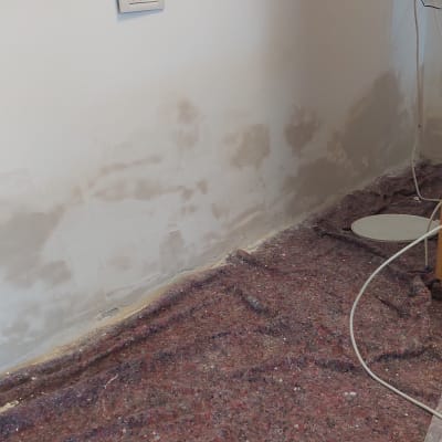 קיר עם תיקוני צבע ושטיח מגן על הרצפה