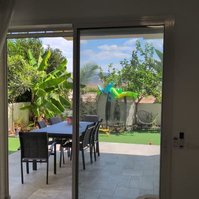 דלת הזזה עם תריסים נפתחים לחצר עם צמחייה