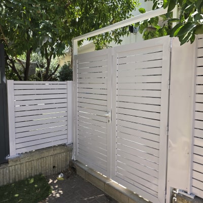 שער אלומיניום לבן עם צמחייה ברקע