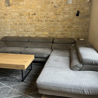 ספה אפורה גדולה ליד שולחן עץ בסלון