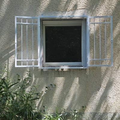 חלון עם סורגים על קיר חיצוני עם צללים