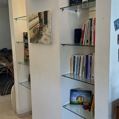 מדפי זכוכית עם ספרים על קיר לבן