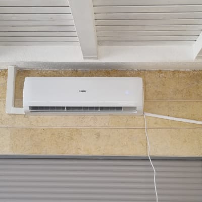 מזגן מותקן על קיר עם צינור חשמל לבן