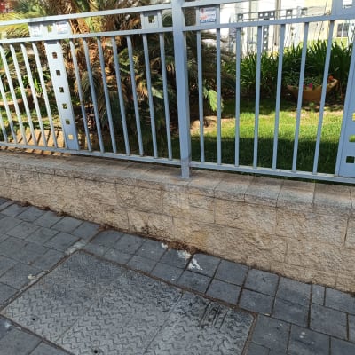 גדר מתכת אפורה עם עמודים מרובעים על מדרכה