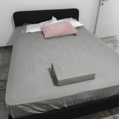 מיטה עם מצעים אפורים וכרית ורודה