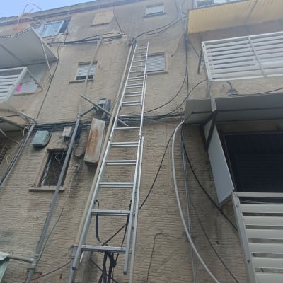 סולם מתכת צמוד לקיר בניין עם צינורות חשופים