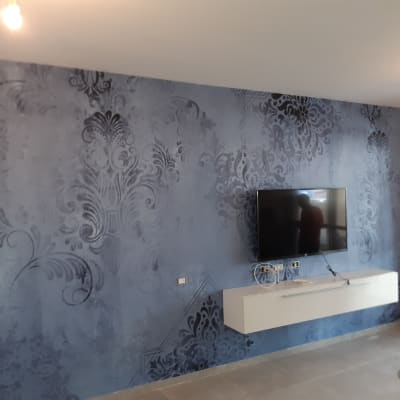 קיר כחול עם דוגמאות דקורטיביות וטלוויזיה תלויה