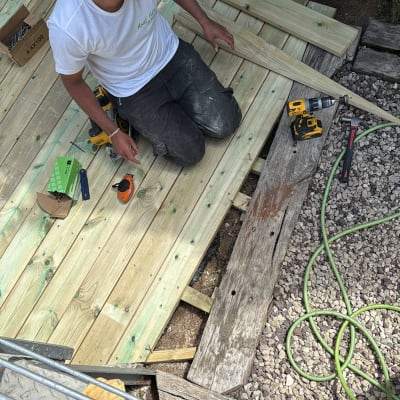 אדם עובד על דק עץ עם כלים חשמליים